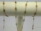 a close up of a gold necklace on a white stand