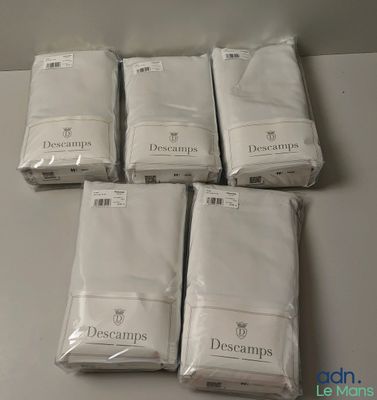 Six paquets de linge de lit blanc sont posés sur une table