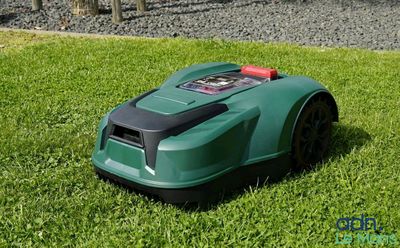 une tondeuse à gazon verte posée au milieu d'un champ recouvert d'une herbe verte et luxuriante
