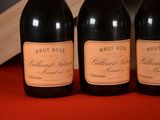 three bottles of brut rose wine sit on a red table