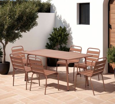 une table et des chaises sur une terrasse, avec une plante en pot