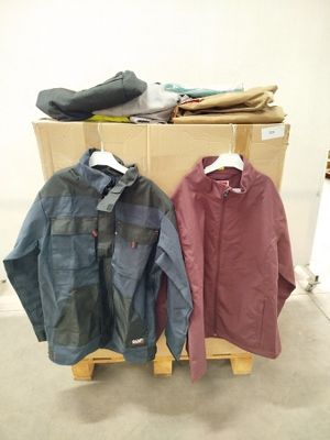 Deux vestes sont suspendues à un porte-manteau devant une pile de vêtements