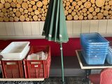 des tables et des chaises devant un magasin avec un parasol vert