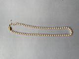 a close up of a gold beaded necklace on a white surface