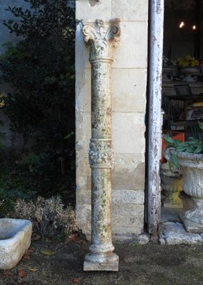 une fontaine en pierre devant un bâtiment, avec une jardinière sur le côté