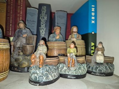 many figurines of people sitting on top of a shelf