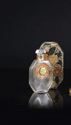 a bottle of perfume next to a gold ring on a table