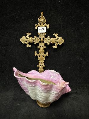 un gros plan d'une croix posée sur un coquillage rose