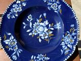 une assiette bleue ornée de fleurs blanches, posée sur une table en bois