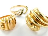 deux bagues en or et une bague posée sur une surface blanche