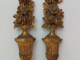 two gold vases with flowers on them sitting on a table