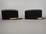 two black hats with gold trims are sitting on a table