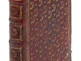 un vieux livre à la couverture rouge posé sur une surface blanche