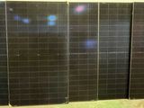three panels of black solar panels are lined up against a wall