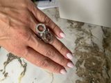 a woman ' s hand holding a diamond ring on a marble table