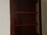 a wooden cabinet in the corner of a bathroom