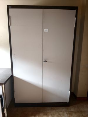 a white cabinet in the corner of a room next to a table