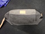 a gray bag with a brown handle on a black carpet