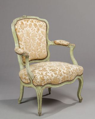 an antique chair with a floral upholstered back and arms