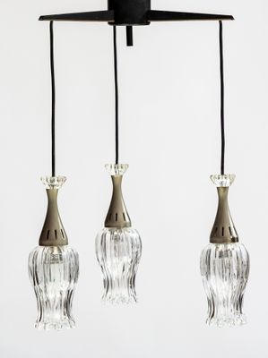 trois suspensions en verre suspendues au plafond dans une pièce blanche