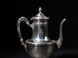 an antique silver teapot on a black background