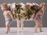 deux figurines tenant un vase orné de fleurs