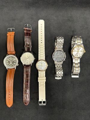 four different watches are lined up on a black surface