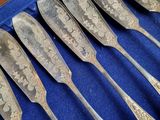 six silver spoons in a blue case on a blue surface