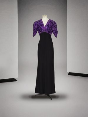 robe de soirée violette et noire posée sur un présentoir pour mannequin