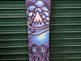 a snowboard leaning against a green wall with a painting on it