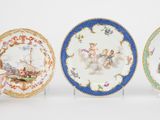 trois assiettes et une tasse sont posées sur un support, sur une surface blanche