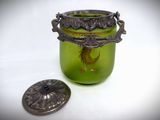a green glass jar with a bird on it next to a coin