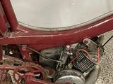 an old red motorcycle with a small engine on the ground