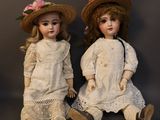 pair of antique porcelain dolls sitting next to each other on a black background