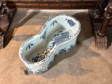 a blue and white vase sitting on the floor next to a wooden bench