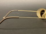 pair of gold colored sunglasses on a black surface