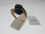 une image d'une bague en or avec une pierre bleue et des diamants