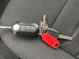 a car key with a red keychain sitting on the seat of a car