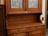 une armoire en bois à deux portes, dont l'une est vitrée