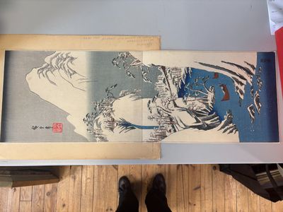 une photo d'une personne debout à côté d'un tableau posé par terre