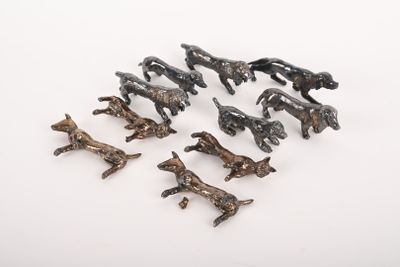 de nombreuses petites figurines de chiens en bronze posées sur une surface blanche