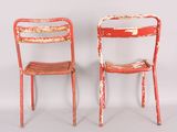 two red chairs sitting next to each other on a white surface