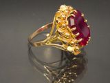 a close up of a gold ring with a red stone in it