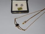 two necklaces and a pair of earrings sitting on a table