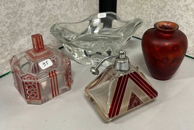 trois récipients en verre posés sur une étagère en verre, à côté d'un vase rouge