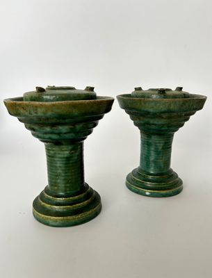 deux vases verts posés l'un à côté de l'autre sur une table