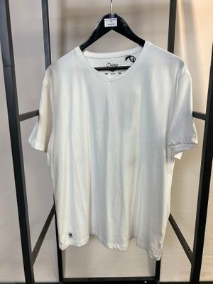 un t-shirt blanc accroché à un portant dans une pièce