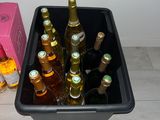 bottles of beer in a black container next to a pink box on the floor