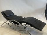 a black leather chaise lounger and ottoman in a studio setting