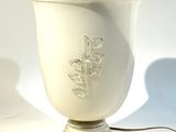 un vase blanc posé sur une table, auquel est attaché un cordon